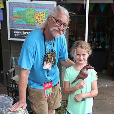 Curt Krob, Demonstration artist and First Treasures participant poses with young child and her First Treasures selection.